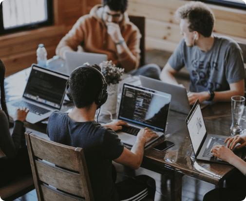 People collaborating around a table with laptops